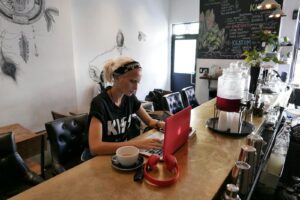 Woman engaged in blogging with a laptop at a trendy cafe in Brooklyn, NY.